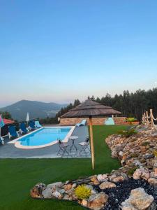 a pool with an umbrella and chairs and a table at Refúgio in Castelo de Paiva