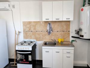 a small kitchen with a stove and a sink at El Rincón de km8 in Comodoro Rivadavia