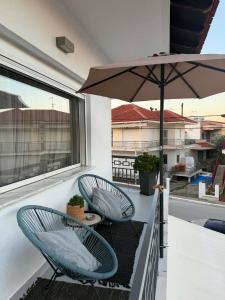 two chairs and an umbrella on a balcony at Angel's Luxury Studio in Olympiada
