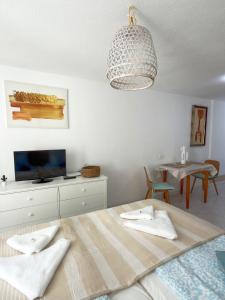 a room with a bed and a table and a chandelier at Cactus Apartment in Playa Fañabe