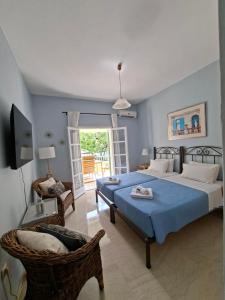 a bedroom with a large bed and a chair at Kipos Apartments in Kassiopi