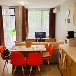 a kitchen and living room with a table and red chairs at Студио Стайл - Соренто Соле Маре in Sveti Vlas