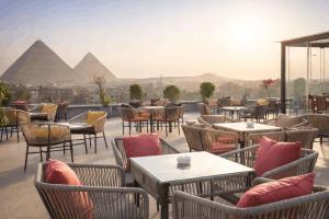 a restaurant with tables and chairs with pyramids in the background at Pyramid Front Hotel in Cairo