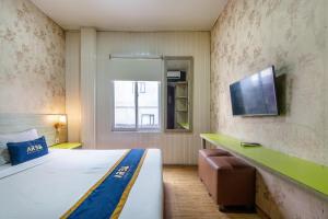 a hotel room with a bed and a tv on the wall at Hotel Aleander By ARBA in Jakarta
