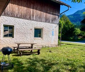 a picnic table and a grill next to a building at The Yugo House in Bohinj