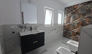 a white bathroom with a sink and a mirror at MarioLia Comfort Residence in Oradea
