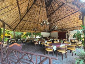 a restaurant with tables and chairs and a straw roof at Ecotel Quinta Regia in Valladolid