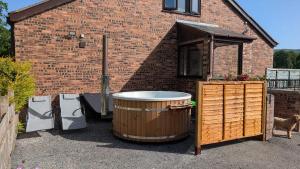 a hot tub sitting next to a brick building at Owl's Watch in Ruthin
