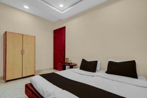 a bedroom with a large white bed with black pillows at HOTEL O INNORA in Raipur