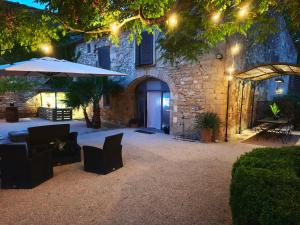 a patio with an umbrella and chairs and a building at Maison d'hôte Mas de Castille entre Uzès et le pont du Gard in Argilliers