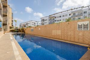 a blue swimming pool in front of a brick wall at Eden Appartement avec Piscine Et Salle de Sport in El Jadida