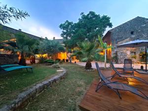a yard with two chairs and an umbrella at Maison d'hôte Mas de Castille entre Uzès et le pont du Gard in Argilliers