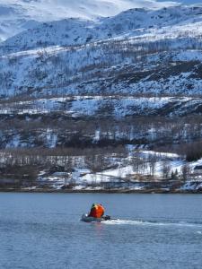 a person in a boat in a body of water at Fjord & Flame in Tromsø