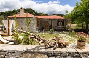 a house with a stone wall in front of a yard at PETRASTERO Mountain Retreat-Agrafa Evrytania Greece in Vérnikon