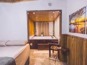 a bathroom with a tub and a bed and a bath room at Cabana com Hidro, Lareira e Piscina Privativa in Chapecó