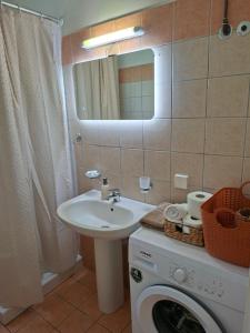 a bathroom with a sink and a washing machine at Kipos Apartments in Kassiopi +33 photos