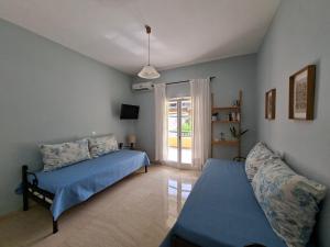 a bedroom with a bed and a couch and a window at Kipos Apartments in Kassiopi