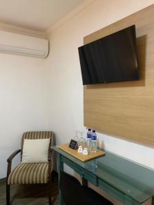 a room with a table and a chair and a television at Pousada Bem te vi in Bragança Paulista