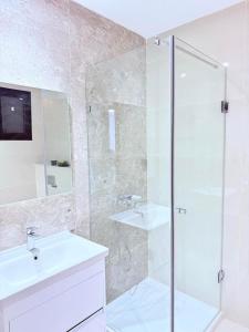 a bathroom with a glass shower and a sink at Résidence jawhret el kram in El Aouina Station