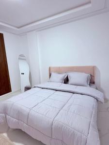 a white bedroom with a large bed with white sheets at Résidence jawhret el kram in El Aouina Station