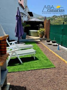a patio with a table and an umbrella and grass at Abadog Canarias in Firgas