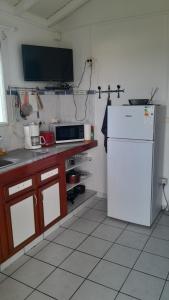a kitchen with a white refrigerator and a microwave at Bungalow vue sur mer in Sainte-Anne