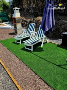 two chairs and an umbrella on a patch of grass at Abadog Canarias in Firgas