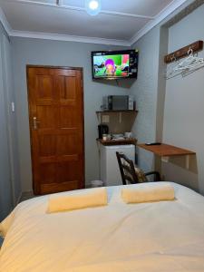 a bedroom with a bed and a television on the wall at Amani Nest in Arcadia