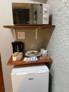 a microwave sitting on a shelf above a refrigerator at Amani Nest in Arcadia