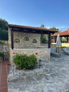 a stone fireplace in a patio with a umbrella at Carlas House, Kalyves in Tsivarás