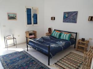 a bedroom with a bed with blue sheets and a rug at Dar Cally Maison d Artiste in Midoun