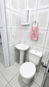 a white bathroom with a toilet and a sink at Estádia aconchegante! in Vilhena