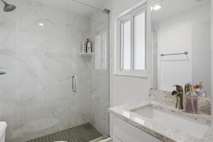 a white bathroom with a shower and a sink at Be A Nomad - 3 Bedroom Apartment 1 Min to Jacksonville Beach - Sleeps 6 in Jacksonville Beach