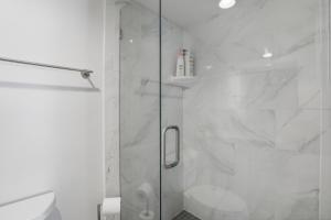 a white bathroom with a shower with a glass door at Be A Nomad - 3 Bedroom Apartment 1 Min to Jacksonville Beach - Sleeps 6 in Jacksonville Beach +14 photos