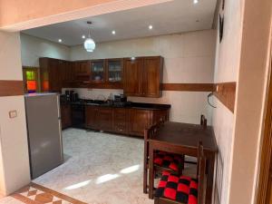 a kitchen with wooden cabinets and a table and a refrigerator at Villa ETAHIRI in Marrakesh