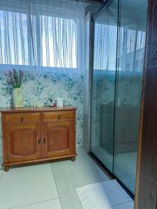 a bathroom with a shower and a wooden cabinet and a glass shower stall at Casa Astral in Chapada dos Guimarães +35 photos