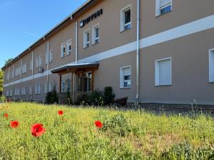a building with red flowers in a field of grass at City Inn Schwedt in Schwedt