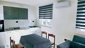 a kitchen with white cabinets and a table and chairs at Apartmani Bradaric Hvar in Gdinj