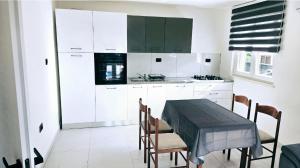 a kitchen with white cabinets and a table and chairs at Apartmani Bradaric Hvar in Gdinj