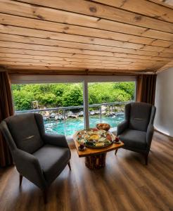 two chairs and a table in a room with a view at Ayder River Suite by Karadeniz in Ardeşen