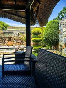 two benches sitting under a thatched roof at Mukani B&B in Lobatse