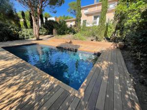 a swimming pool with a wooden deck next to a house at Villa Arethuse - Pyla sur Mer in Pyla-sur-Mer