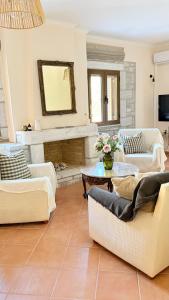 a living room with white furniture and a fireplace at Casa SanGiorgio Stone Villas with Sea View in Skaltsotiánika