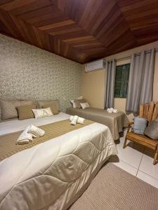 a bedroom with two beds and a chair at Casa Astral in Chapada dos Guimarães
