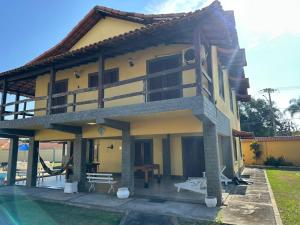 a large yellow building with a pool in front of it at Casa Bella Itaúna Suites in Saquarema