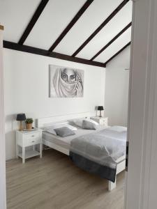 a white bedroom with a bed and a painting on the wall at Apartment Eleni in Šibenik