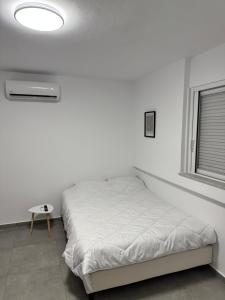 a white bedroom with a bed and a table at Hera in Verga Kalamata