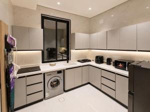 a kitchen with white cabinets and a washer at إليت إن - ELITE INN Serviced Apartments in Qal'at Bishah