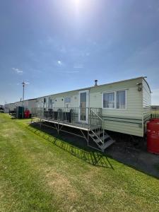 a mobile home with a porch and a deck at Klara Happy Days in Trusthorpe