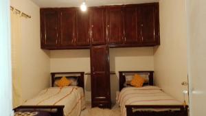 two beds in a room with wooden cabinets at Gite Tilouguite in Tillouguit nʼAït Isha +4 photos